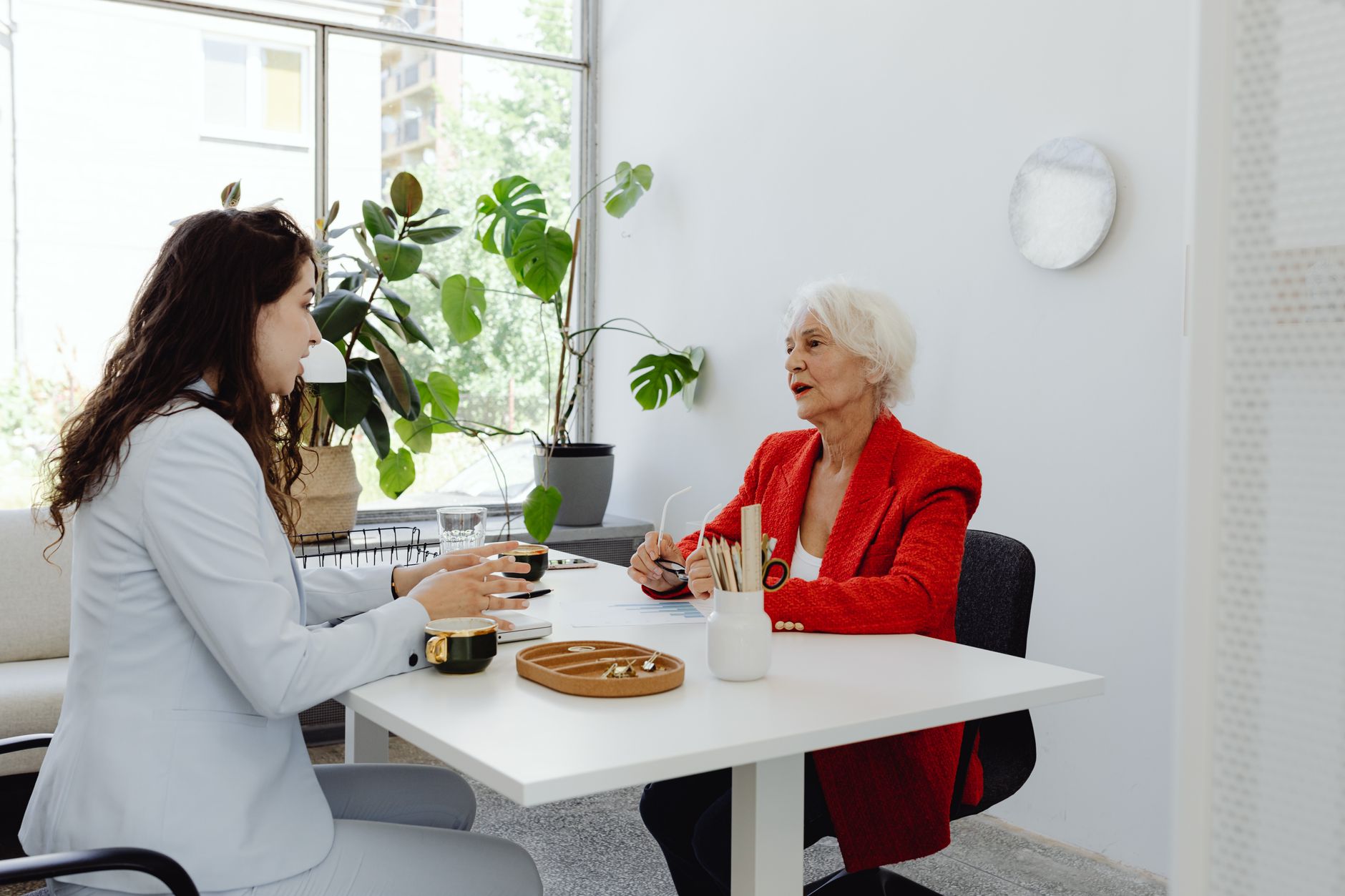 Two people talking across a table in a bright room