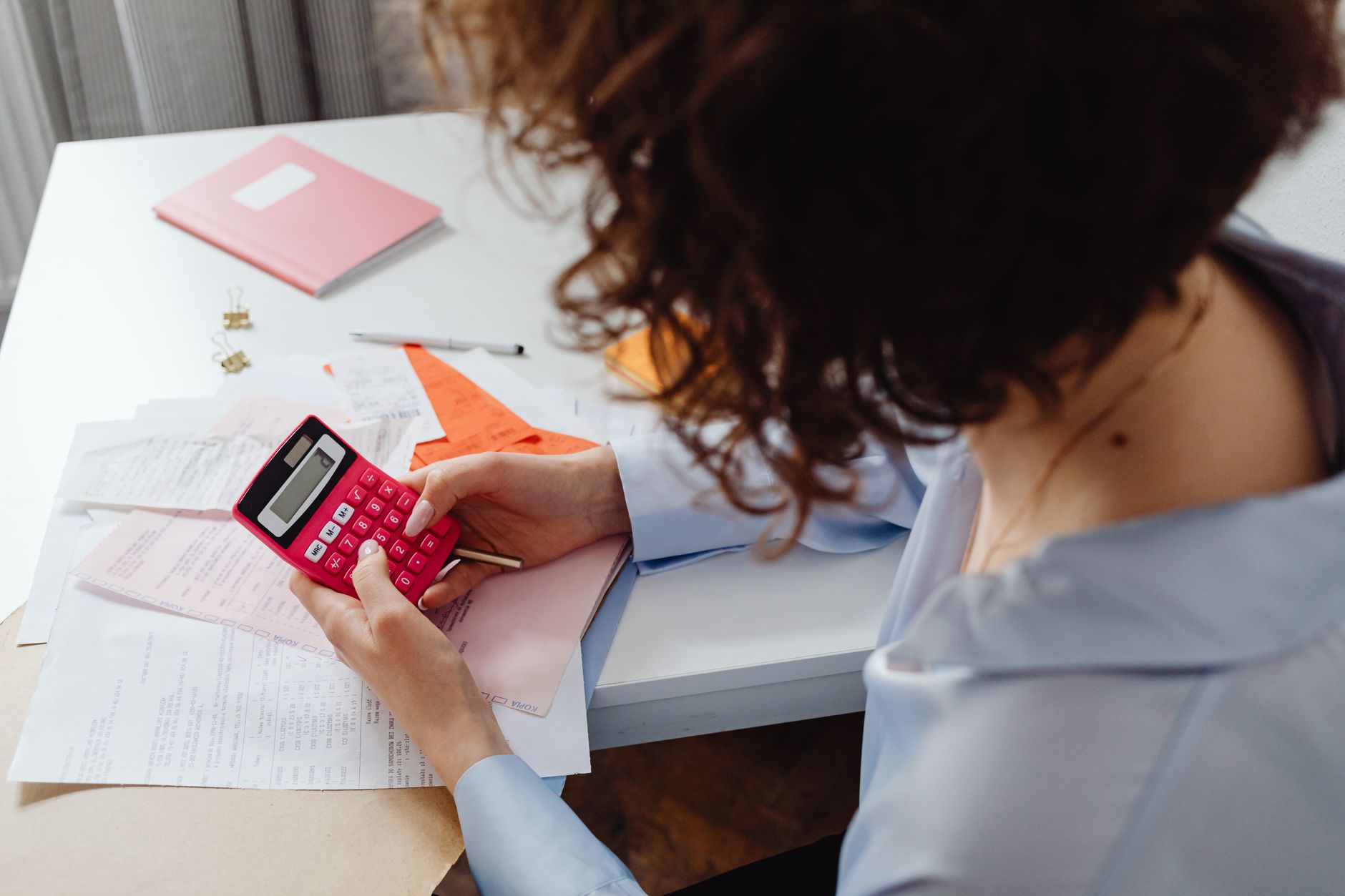 Person using a calculator beside household paperwork