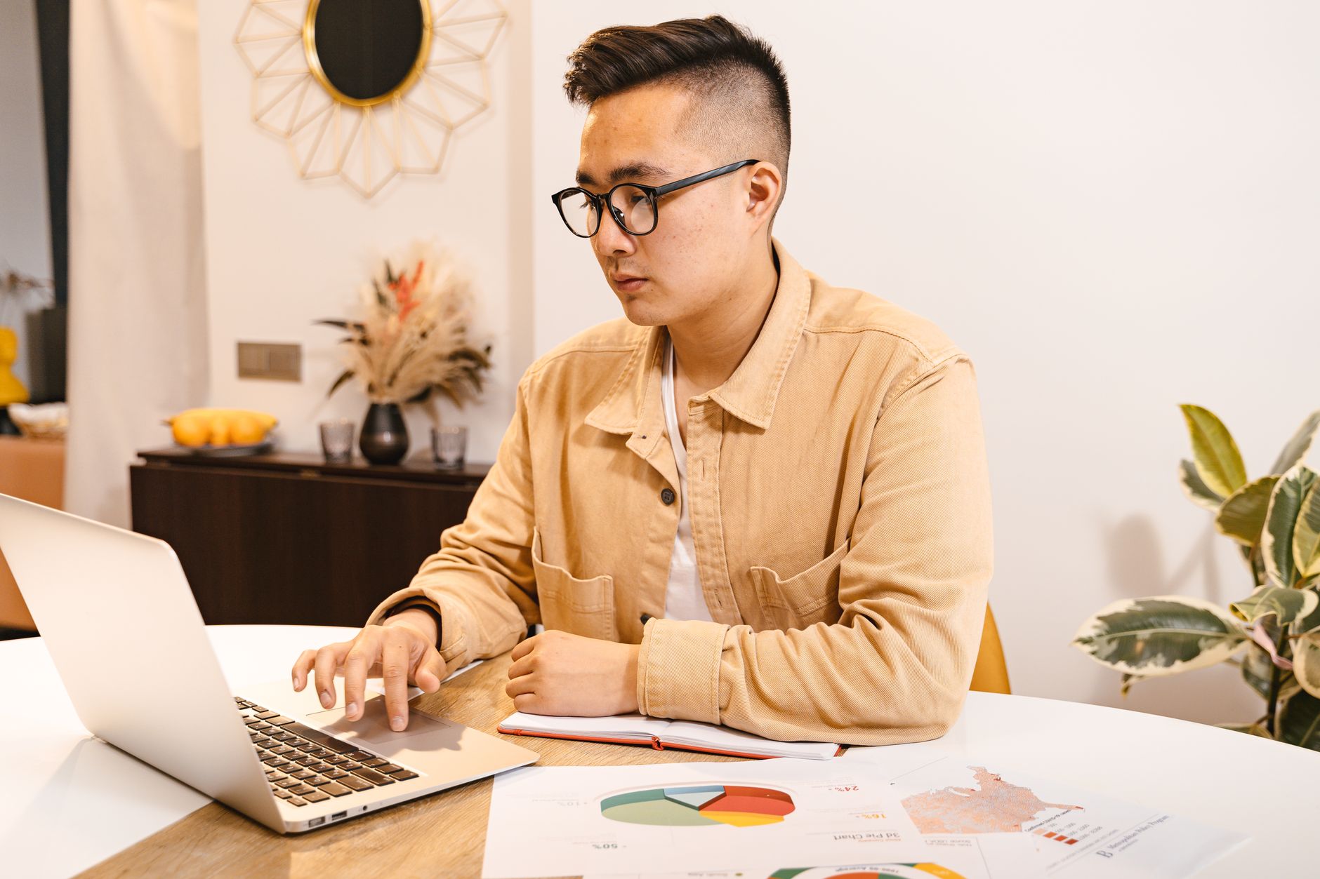 Person reviewing documents and charts at a laptop